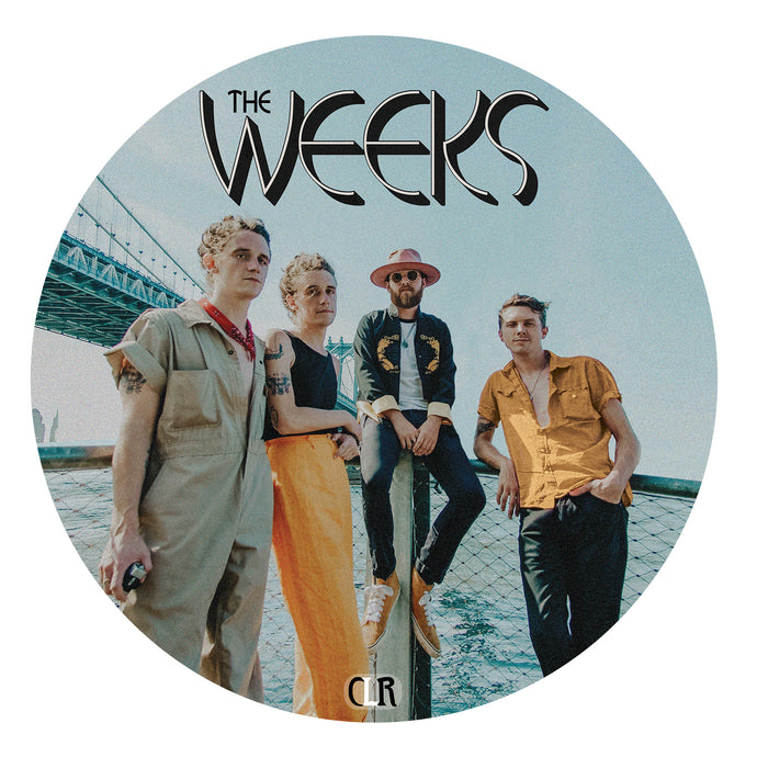 Image of a circular vinyl slipmat against a white background. The slipmat features the album artwork from the week's album twisted rivers. It is an image of the 4 members standing and leaning against a fence with water and a bridge behind them. One member is sitting on the fence. above their heads in white text with a black outline reads the weeks.
