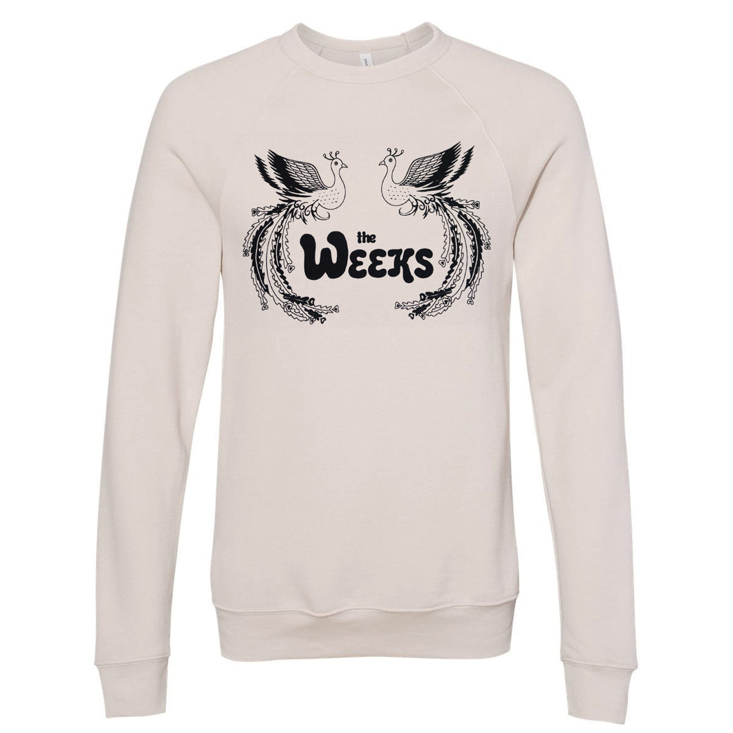 Image of a heather dust/white colored crewneck against a white background. The center of the crewneck in black text says the weeks. On each side of this text there is a peacock, they are looking at each other. The peacocks are outllined in black and not filled in with any color, they are just a mix of black and the color of the shirt.