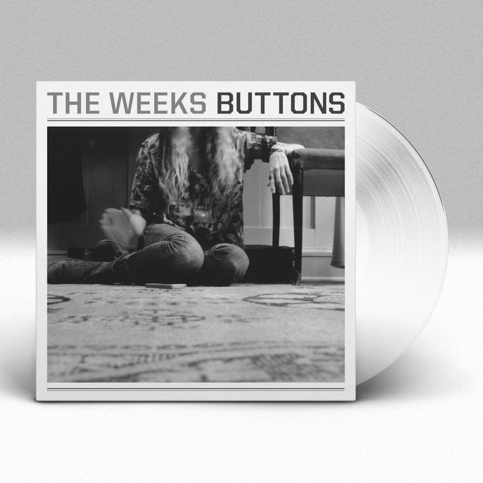 Image of a vinyl sleeve with a white colored vinyl sticking out of the vinyl sleeve against a grey and white gradient background. The vinyl sleeve says The weeks, buttons across the top in grey and black. Below that is a black and white image of a person with long hair sitting on the floor, with one arm resting on a table. You cannot see their face.